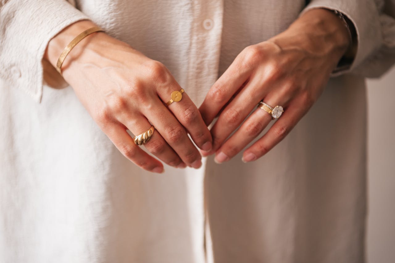 Close-up of hands adorned with elegant gold rings and bracelet.